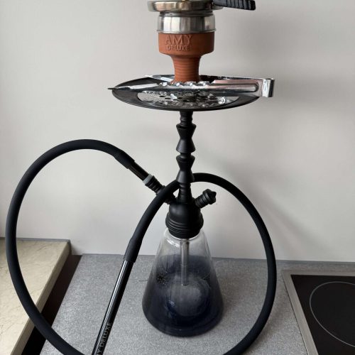 Rauchsäule mit Shisha, Wasserpfeife und Zubehör auf einem Tisch.