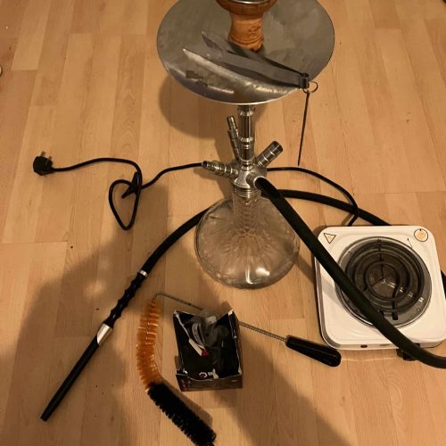 Shisha mit Zubehör, inklusive Reinigungsbürste und Heizplatte, auf Holzboden.