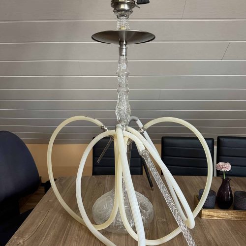 Rauchsäule mit Glasaufsatz, Schlauch und Metallteile, auf Holztisch in Innenraum.