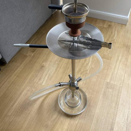 Rauchsäule mit Shisha, Tabak und Zubehör auf Holzboden.