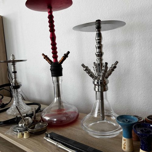 Zwei Shishas mit mehreren Köpfen und Zubehör auf einem Tisch, bereit zum Rauchen.