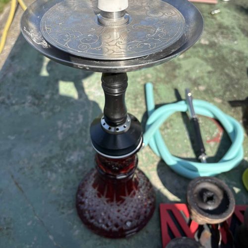 Shisha mit Glasbowl und Zubehör auf Außenfläche.