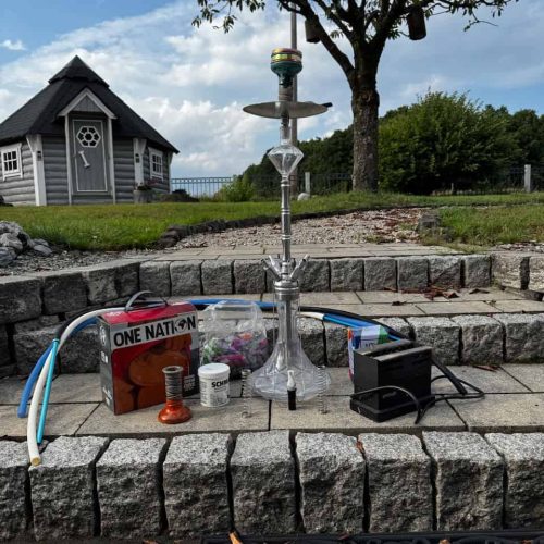 Rauchsäule mit Shisha auf einer Terrasse im Garten, mit Zubehör und Wasserpfeife. Perfekt für entspa.