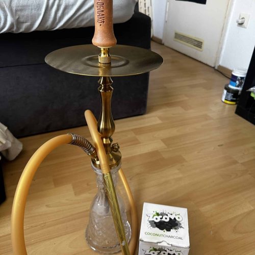 Shisha mit goldfarbenem Schlauch und Kohleaufsatz.