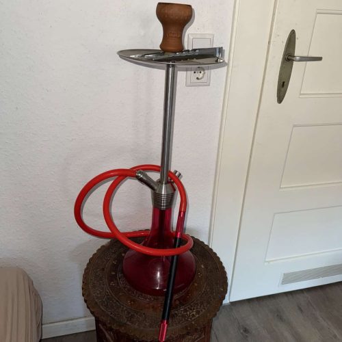 Wasserpfeife mit Zubehör auf einem kleinen Tisch, gut gepflegt.
