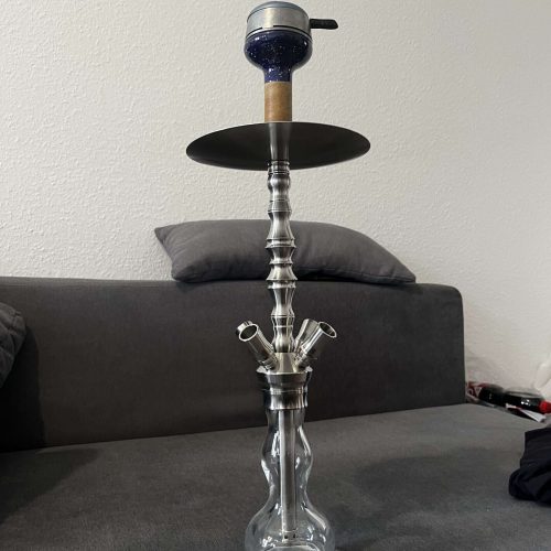 Rauch-Hookah auf einem Sofa mit Zubehör im Hintergrund.