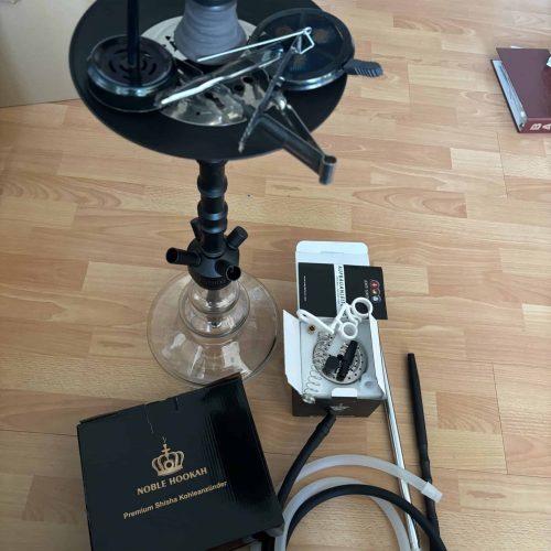 Shisha mit Zubehör und Rauchrohr auf Boden, Zubehörteile sichtbar.