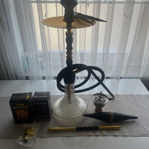 Shisha mit Zubehör, Tabak, Zange und Kohle auf Tisch.