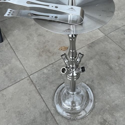 Edelstahl-Shisha mit Glasbasis und Zubehör, auf Fliesenboden.
