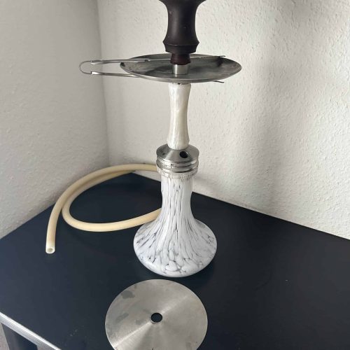 Shisha mit Kopf, Schlauch und Ablage auf schwarzem Tisch.