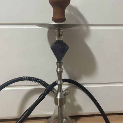 Shisha mit Glasgefäß, Kopf und Schlauch, auf Boden stehend.