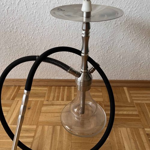 Shisha-Kopf mit Glasbowl und Schlauch auf Holzboden.