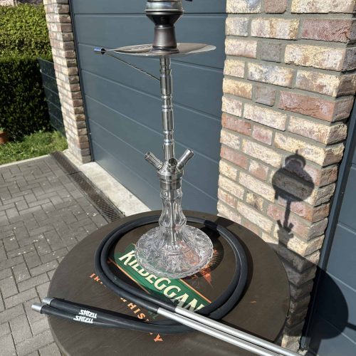 Rauch-Hookah auf einem Tisch mit Zubehör, vor einer Garage im Freien.