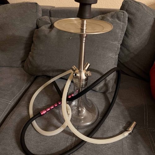 Rauchsäule mit Shisha-Kopf, zwei Schläuchen und Ablage auf einem Sofa.
