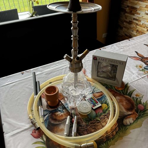 Rauchsäule mit Shisha, Schlauch, Tabak und Zubehör auf Esstisch.