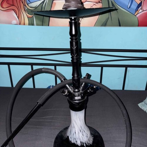 Schwarze Shisha mit Wasser und Rauch, auf einem Tisch.
