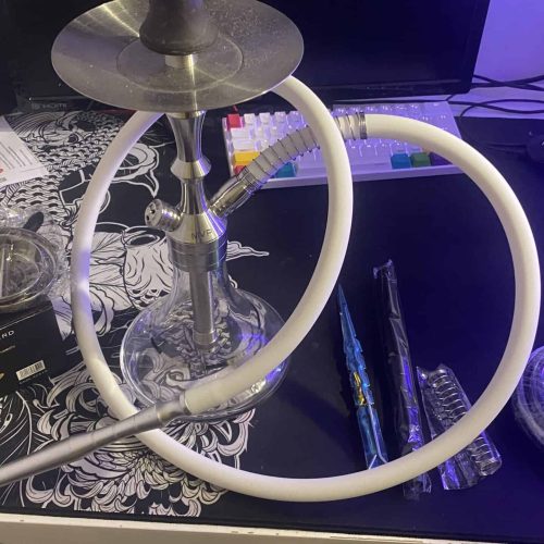 Shisha mit Silikonschlauch und Tabak auf Tisch.