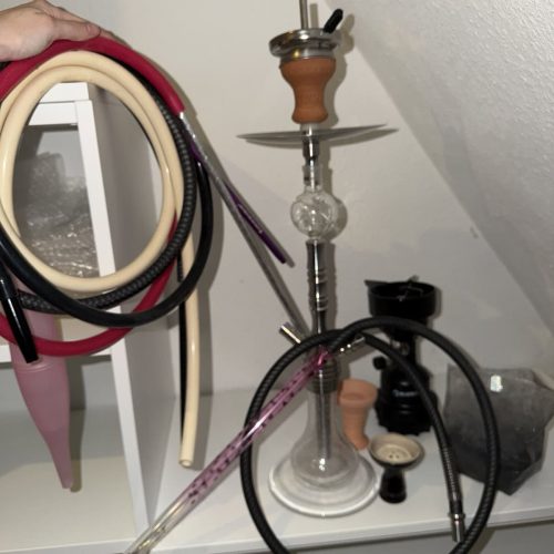 Shisha mit Rauchsäule und Zubehör auf einem Tisch.