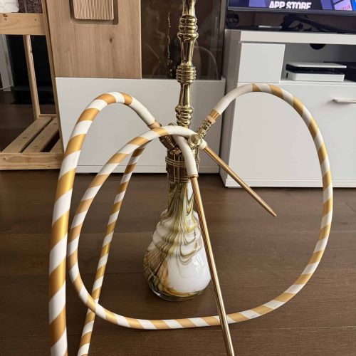 Hookah mit goldener Basis und bunten Schläuchen auf Holztisch.