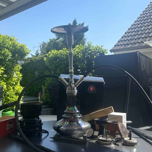 Shisha mit silbernem Kopf und schwarzem Schlauch im Außenbereich.