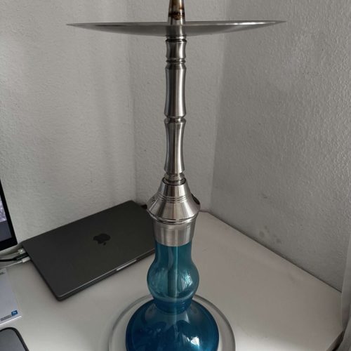Moderne Shisha mit blauer Glasbasis und Metallhals auf Schreibtisch.