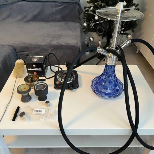 Rauchsäule mit Shisha-Kopf, Schlauch und Zubehör auf einem Tisch. Perfekt für gemütliche Abende.