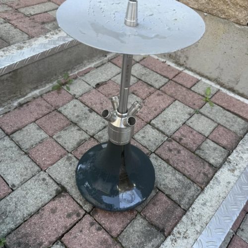 Metallischer Shisha-Tisch mit Glasplatte auf Pflasterstein.