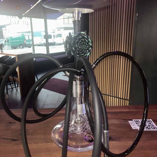 Moderne Shisha mit Rauchsäule auf Holztisch im Café.