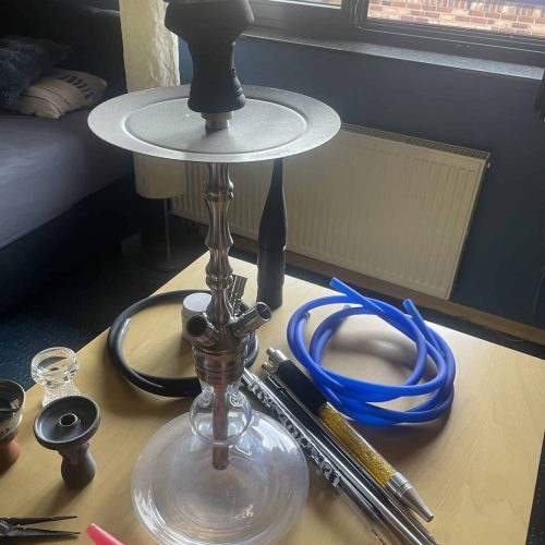 Rauchsäule mit Schlauch, Tabakzubehör und Ersatzteilen auf Tisch.