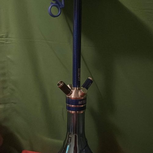 Shisha mit Glasbowl, Schlauch und Zubehör auf rotem Stoff.