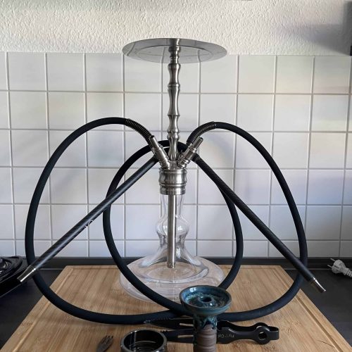 Shisha mit Glasbowl, Schlauch und Zubehör auf Holztablett.