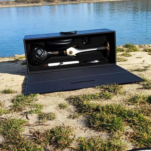 Entspannungs-Set mit Wasserpfeife und Zubehör am Fluss, ideal für Outdoor-Genuss.