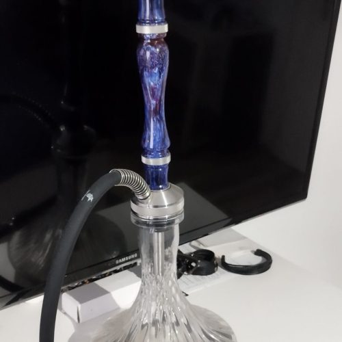 Shisha mit blauer Glasbasis und Metallaufsatz, rauchend auf einem Tisch.