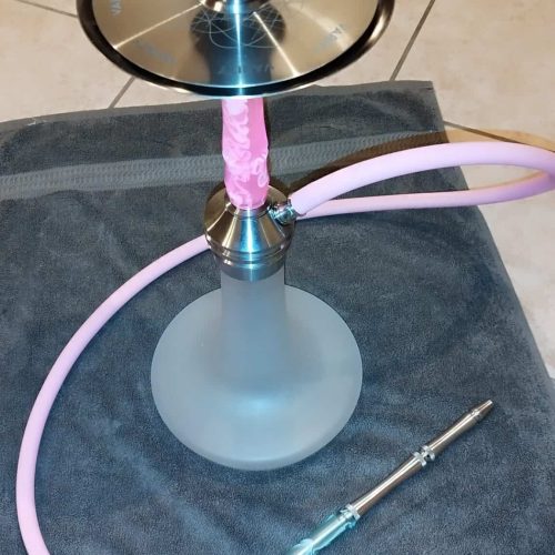 Shisha mit Glasbowl und Silikonschlauch, auf dunklem Tuch liegend, für Raucherlebnis.