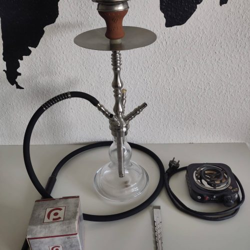 Raucherset mit Shisha, Tabak, Kohle und Zubehör auf weißem Tisch.