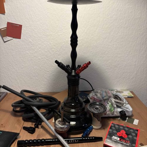 Schwarze Shisha-Hookah mit Glasbowl und Zubehör auf Tisch.
