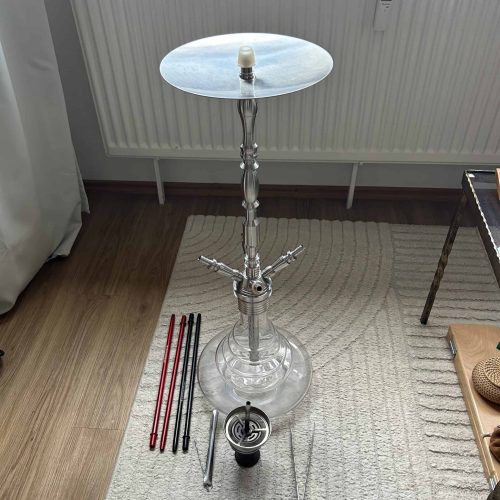 Shisha-Kopf mit Glasbowl, Schlauch und Zubehör auf Boden.