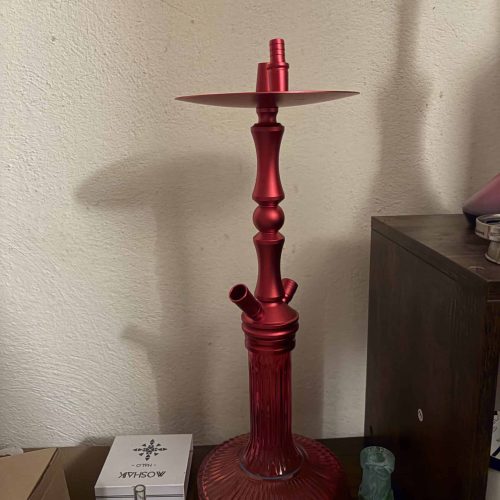 Roter Glas-Kerzenhalter auf einem Tisch, ohne Kerze.
