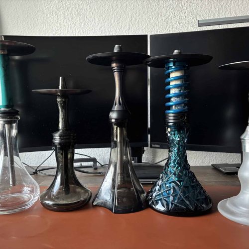 Verschiedene Shishas in unterschiedlichen Designs und Farben auf einem Tisch.