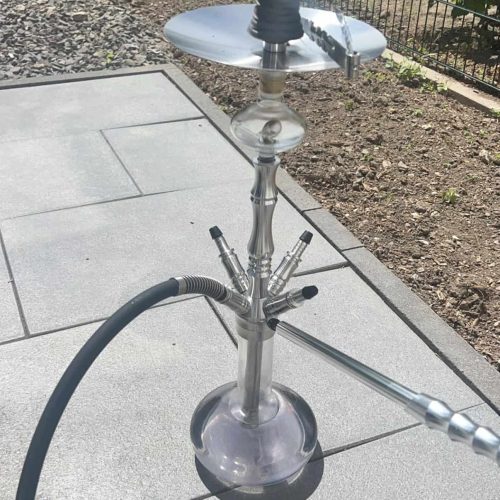 Shisha-Kopf mit Glasbowl und Schlauch auf Terrasse.