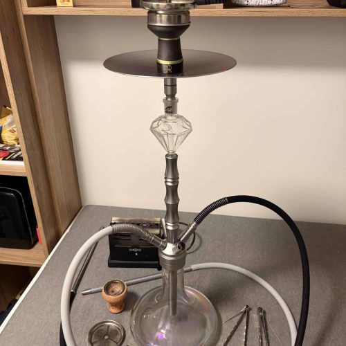Rauchsäule mit Shisha, Tabak und Zubehör auf einem Tisch.