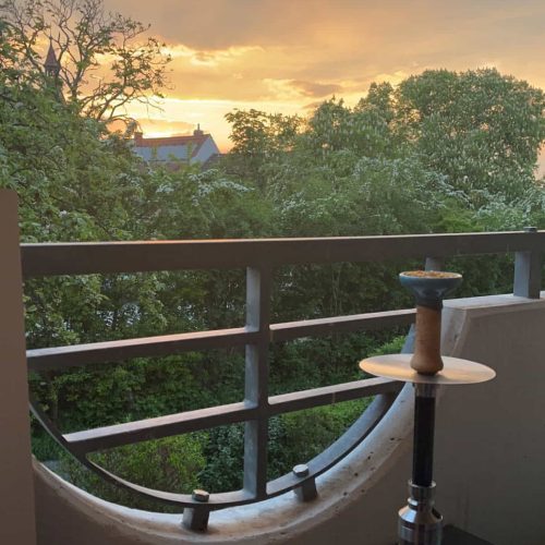 Shisha auf Balkon mit Blick auf den Sonnenuntergang und Bäume.