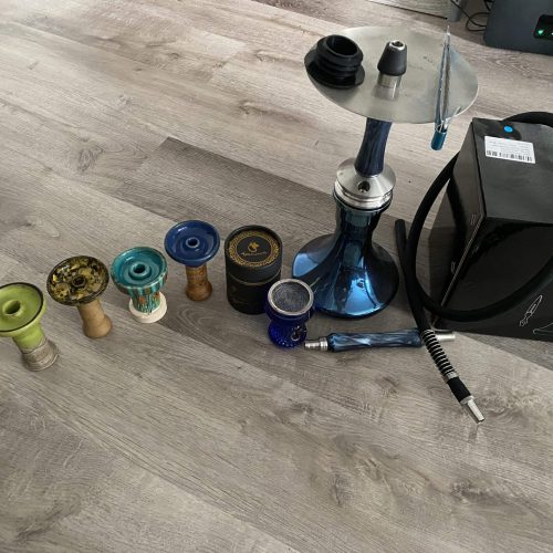 Verschiedene Shisha-Teile und Zubehör auf Holzboden.
