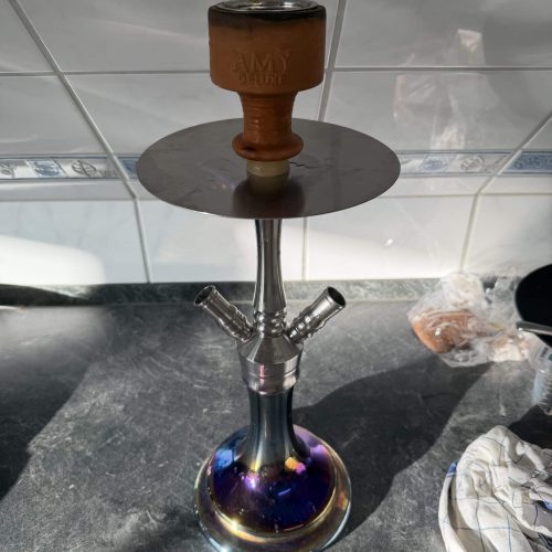 Shisha mit Tonkopf auf einer schwarzen Oberfläche, Hintergrund Fliesen.