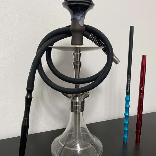 Shisha mit Glasbowl, Schläuchen und Zubehör auf Tisch.