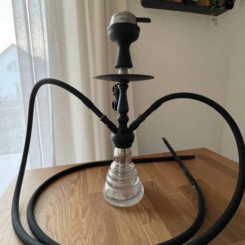 Shisha mit Glasbowl, Schlauch und Kopf auf Holztisch.