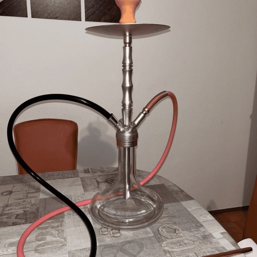 Rauch-Hookah mit Glasbasis, Metallstamm und Silikonschlauch auf Esstisch.