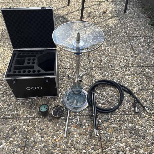 Shisha mit Glasbowl, Schlauch und Zubehör auf Außenboden.