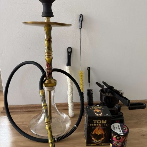 Rauch-Hookah mit Zubehör, inklusive Tabak und Kohle, auf Holzboden gegen weiße Wand.