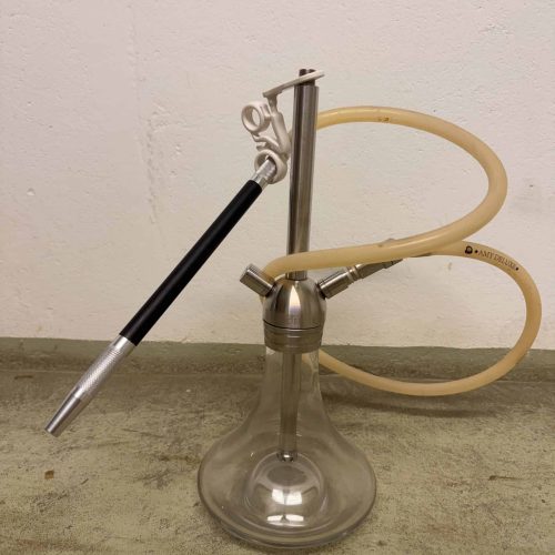 Shisha mit Glasbowl, Metallrohr und Silikonschlauch auf Boden.